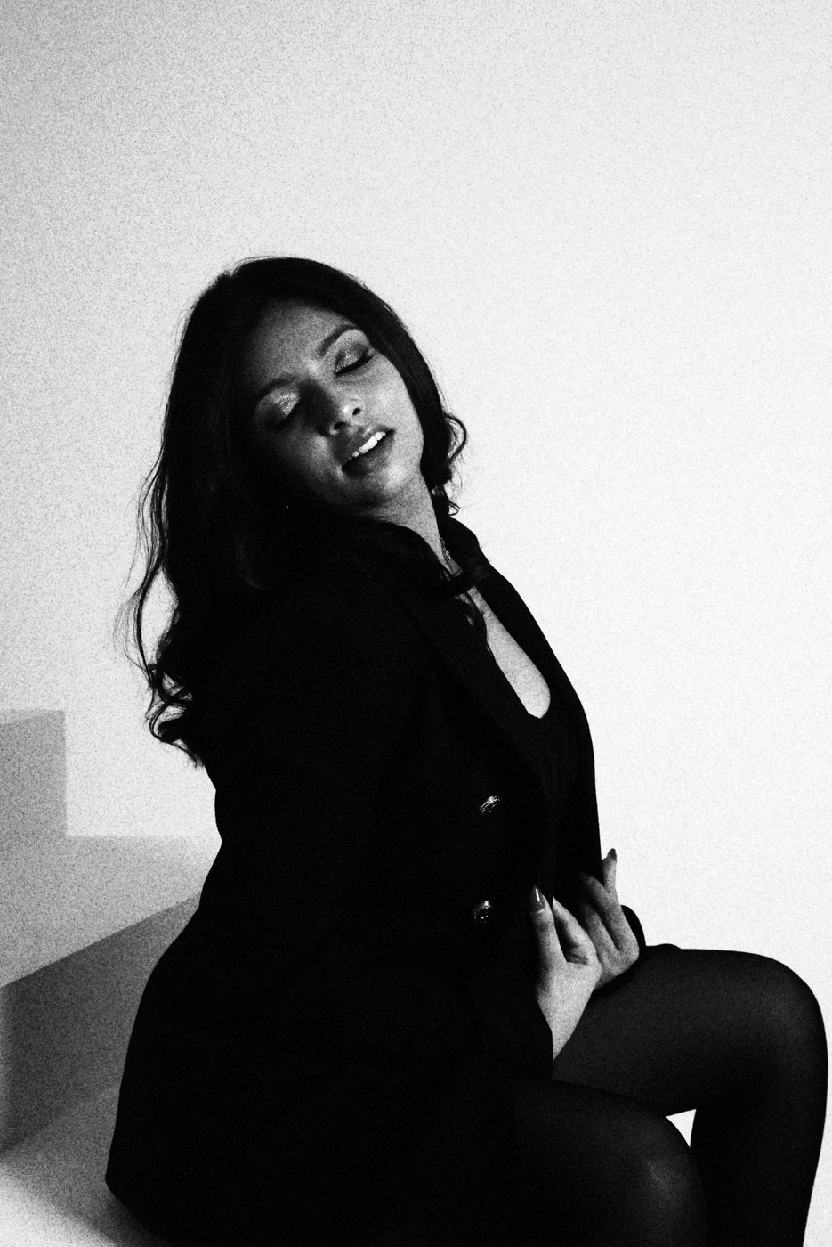 Mrunalini seated in a black blazer, head tilted, black and white portrait