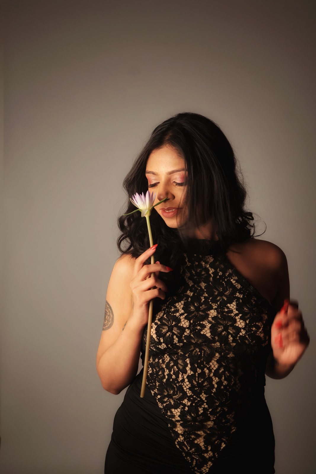 Mrunalini holding a white flower to her face, softly lit